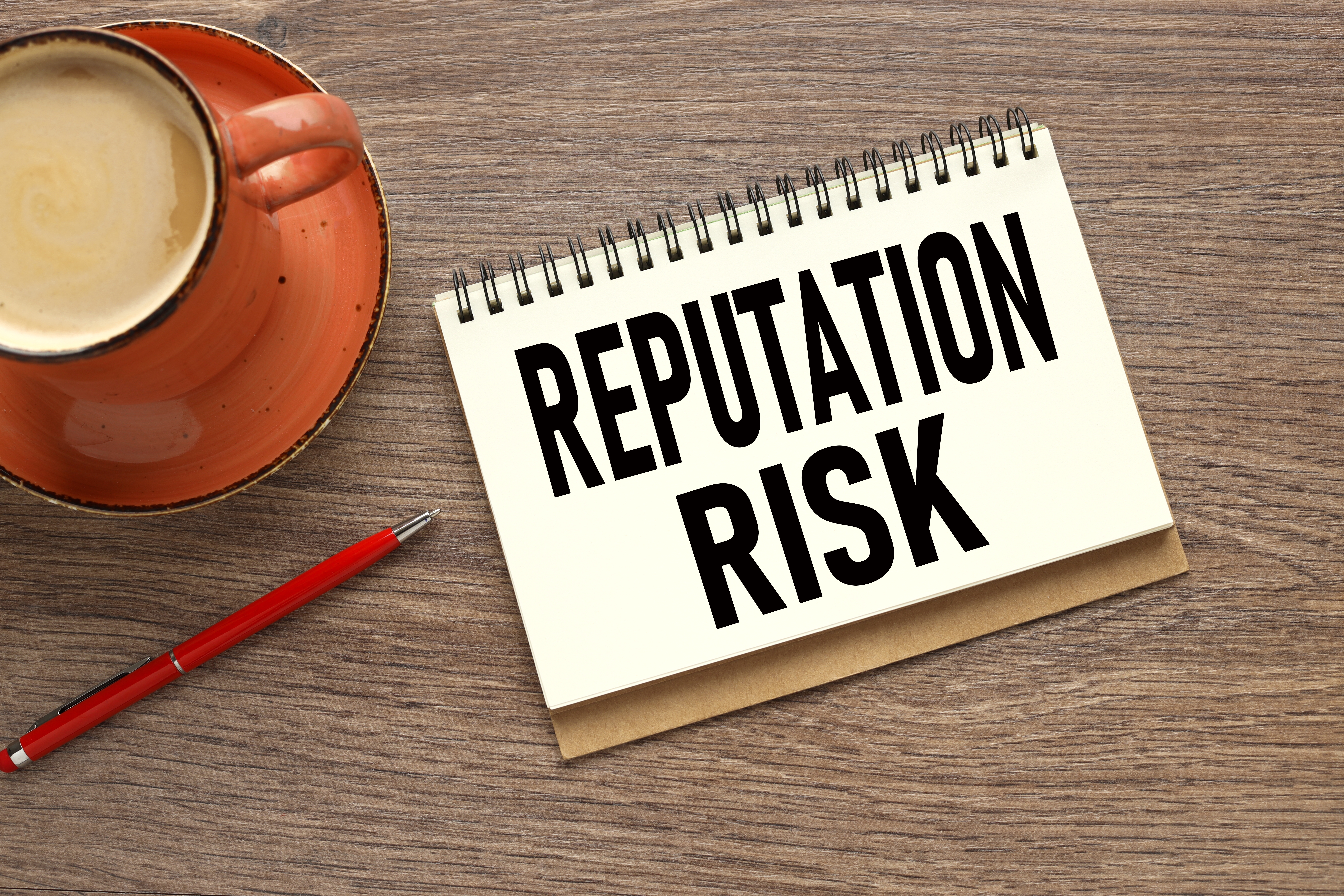 A sign that says 'reputation risk' on it with a cup of coffee.